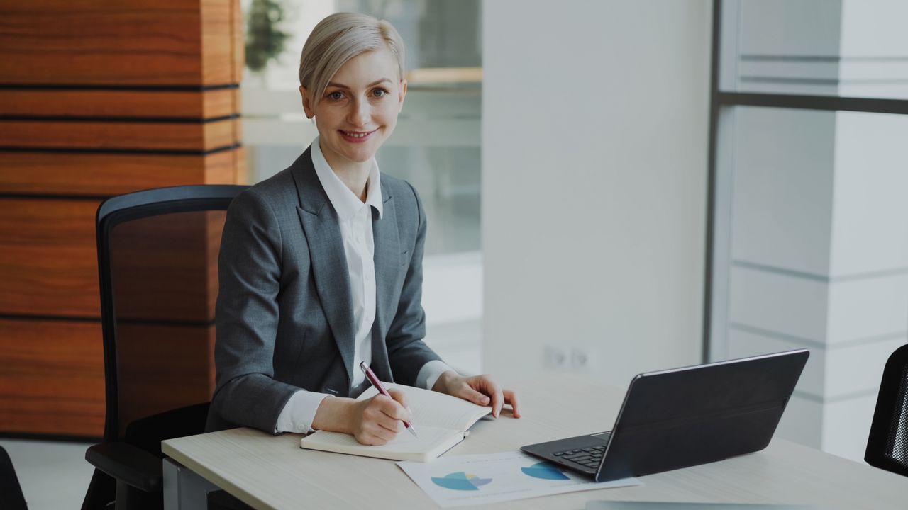 Confident businesswoman taking notes in a contemporary office environment.